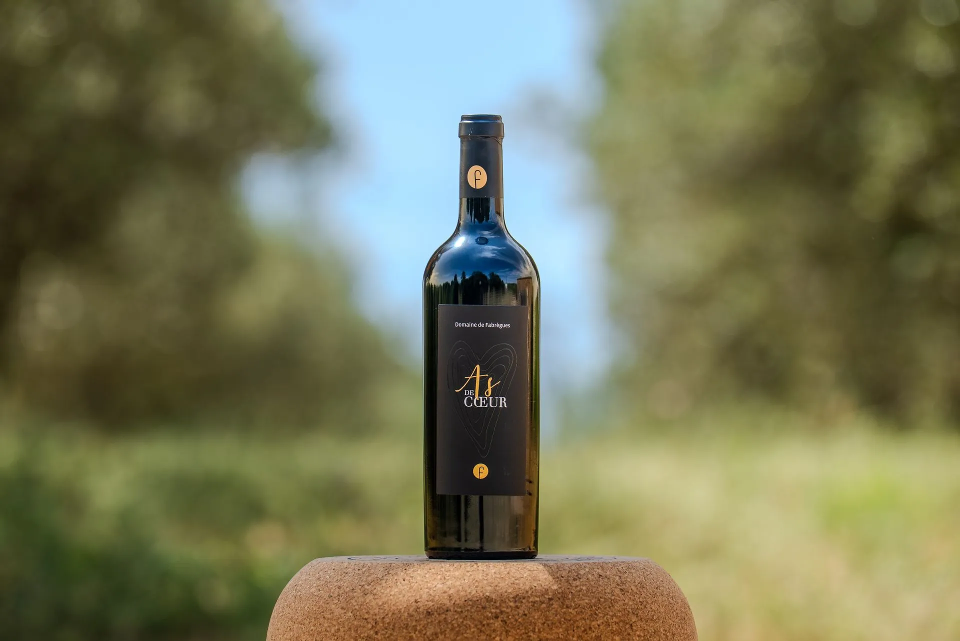 Une bouteille de L'As de Cœur sur fond de verdure