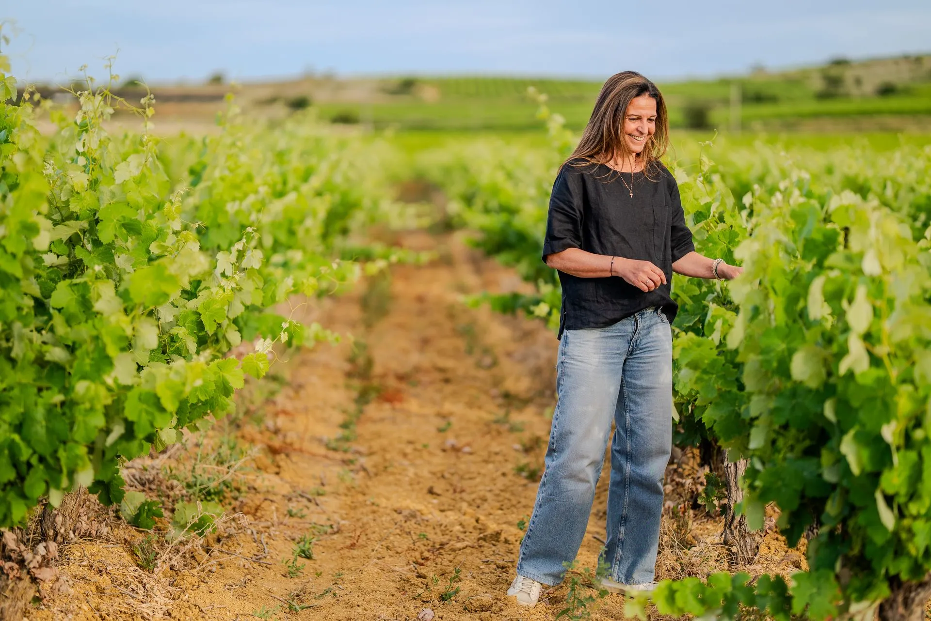 Carine Pichot souriante entre deux rangs de vigne