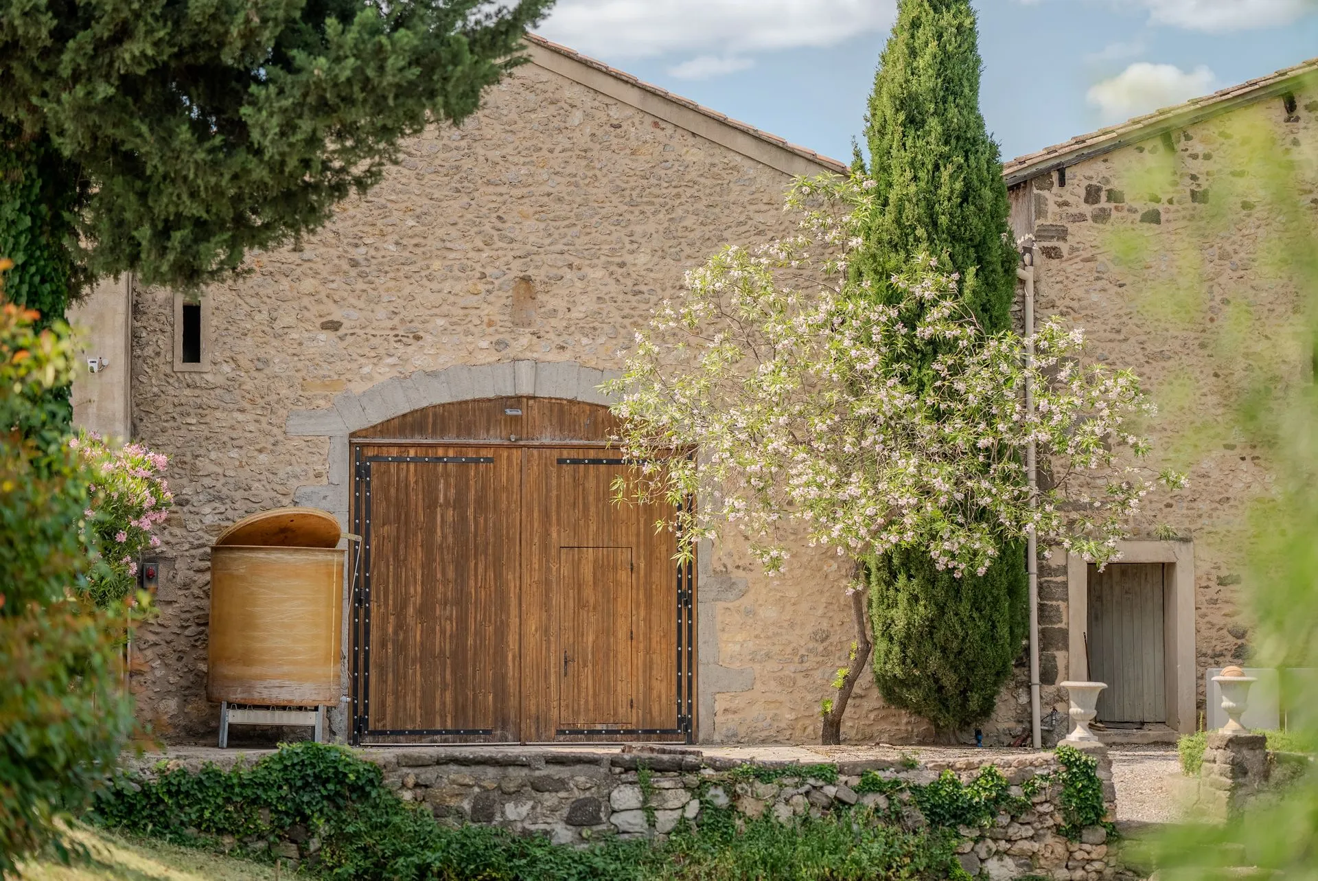 La grande porte en bois de la cuverie, sous un cyprès