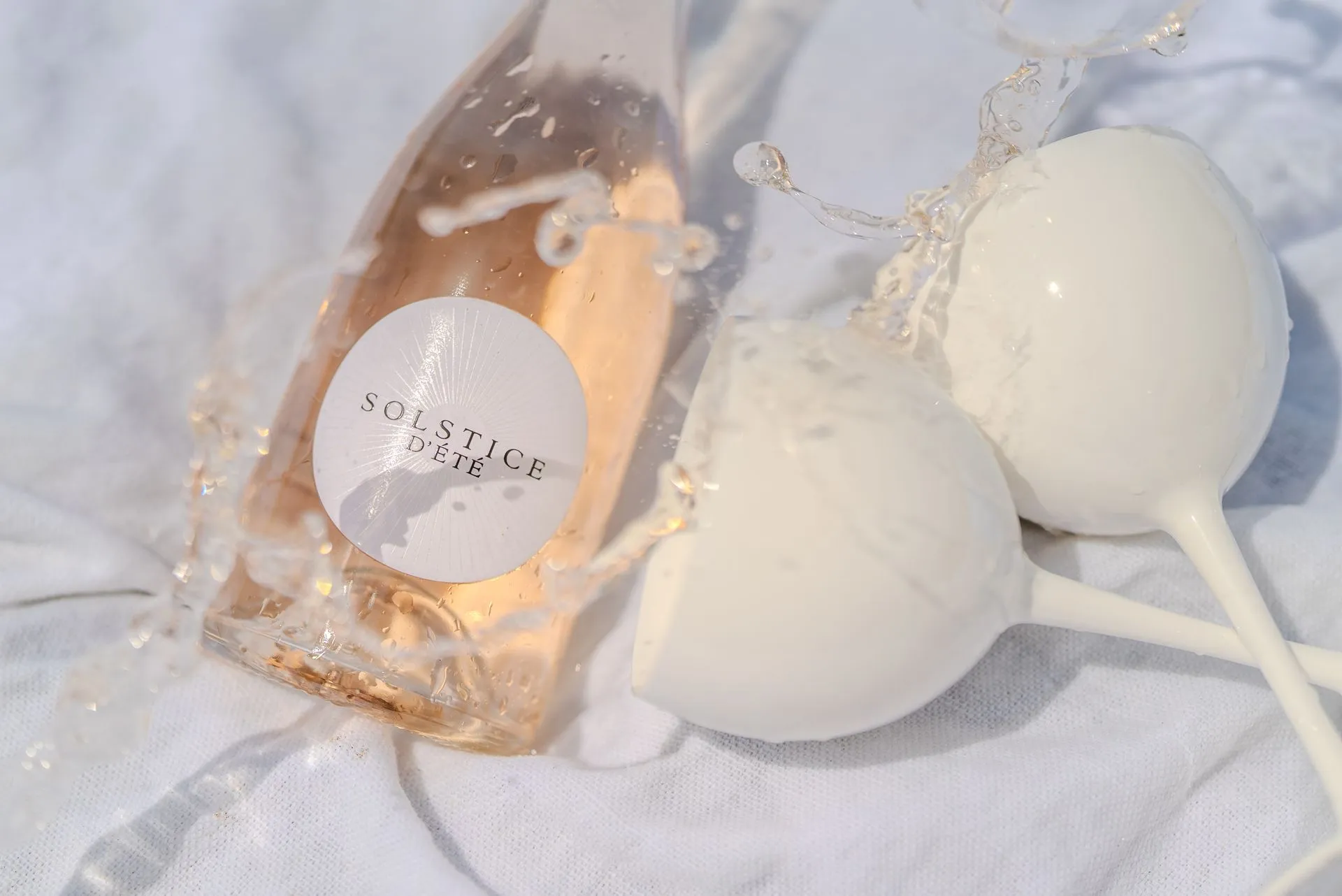Une bouteille de Solstice d'Été rosé et deux verres sur un drap blanc