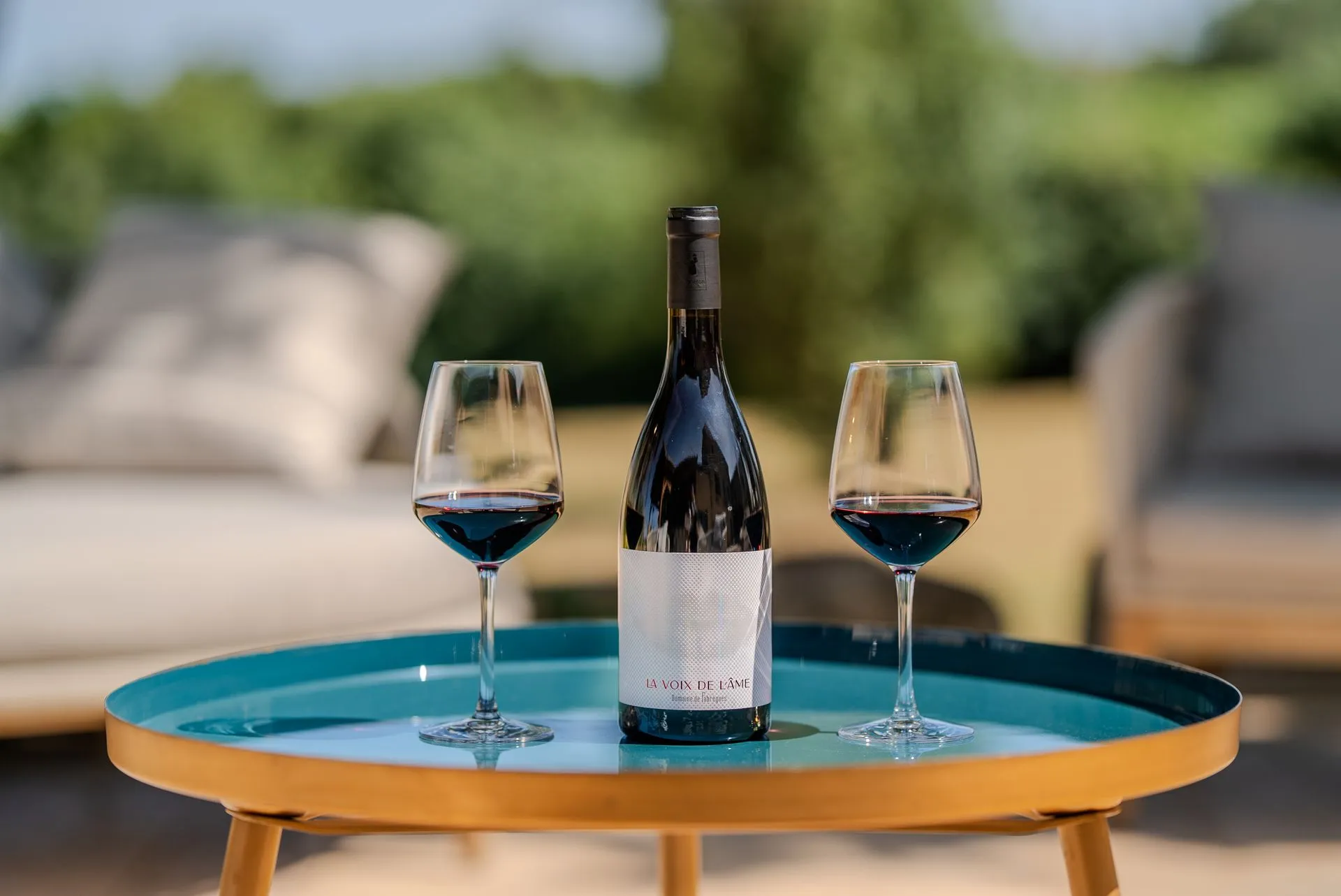 La Voix de l'Âme servie avec deux verres de rouge sur une table de jardin